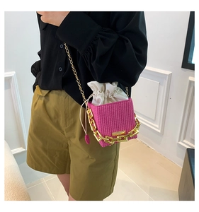 Detail of pink woven crossbody bag featuring bold gold chain and canvas drawstring lining