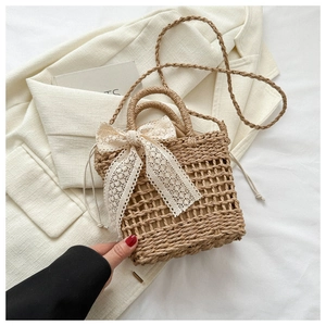 Detail of woven straw bucket bag featuring a white lace bow and drawstring inner pouch