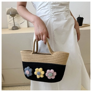 Détail du sac seau tissé avec design color-block et accents de fleurs en peluche colorées