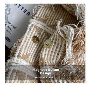 Detail view of the secure magnetic buckle and woven fringe on this stylish beige tote bag