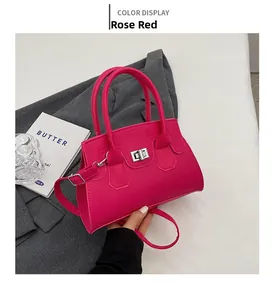 Top handle rose red leather crossbody bag with silver metal clasp on gray suit background