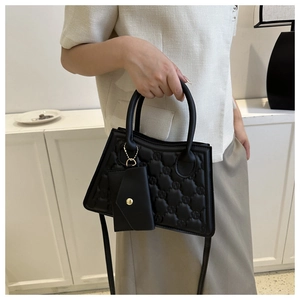 Detail of black quilted PU leather handbag with embossed letters and matching coin pouch
