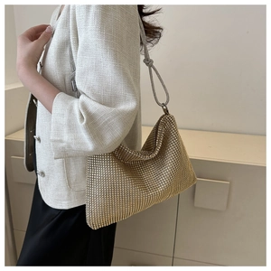Close-up of golden rhinestone hobo bag with a sparkling surface and woven shoulder strap