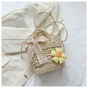 Macro detail of hand-woven straw bag with lace bow, floral accent and drawstring lining