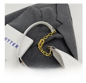 Gros plan d'un sac demi-lune blanc avec chaîne dorée et détail de lame de rasoir