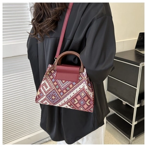 Ethnic embroidered crossbody bag with wooden handles shown in a lifestyle setting