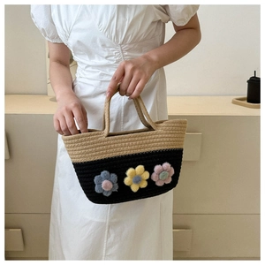 Détail du sac en paille tressée avec cordes bicolores et trois fleurs en peluche 3D