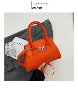Detail of orange faux leather handbag with silver twist lock and slim shoulder strap