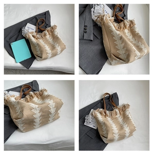 Detail of woven straw tote bag featuring geometric patterns and fringe trim edges