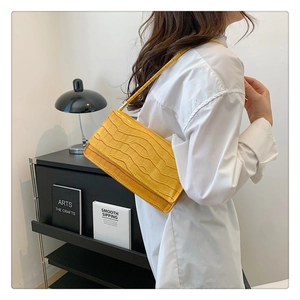 Détail du sac baguette jaune en cuir PU à motif crocodile porté à l'épaule par un mannequin