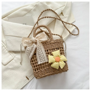 Detail of woven straw bucket bag featuring lace bow and sunflower charm on a suit