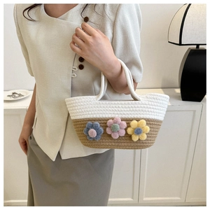 Gros plan du sac seau tissé bicolore orné de trois fleurs décoratives en peluche 3D