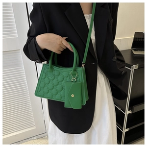 Detail of bright green quilted mini bag with embossed M pattern and matching pendant