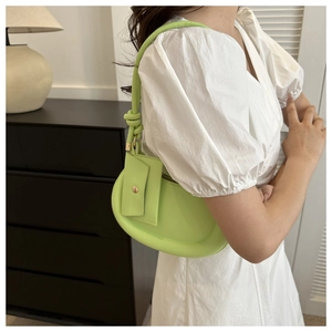 Detail of avocado green crescent bag with wide padded profile and knotted handle detail