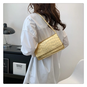 Détail d'un sac sous les bras en cuir doré brillant avec un motif de crocodile élégant