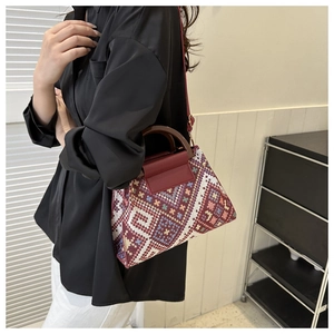 Detail van etnisch geweven crossbodytas met bordeaux leer en een ronde handgreep