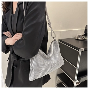 Detailed macro view of sparkling silver rhinestone hobo bag held by a model in a suit