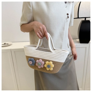 Détail d'un sac cabas tissé main avec des fleurs en peluche 3D et coutures contrastées