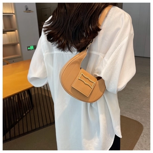 Détail d'un sac à bandoulière marron en forme de croissant avec boucle dorée élégante
