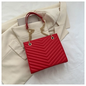 Close-up of red chevron-quilted tote bag with golden metal chain and leather straps