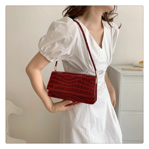 Détail de la texture en cuir crocodile rouge foncé sur un sac à main élégant