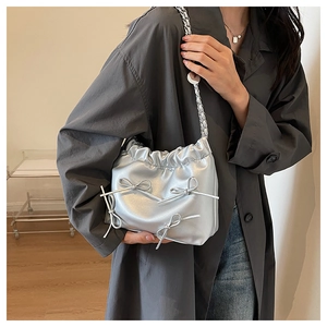 Silver metallic pleated handbag with ribbon bows and chain strap shown on model