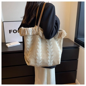 Detail der Strick-Tote-Bag mit beigem geometrischem Muster und dekorativem Quasten-Saum