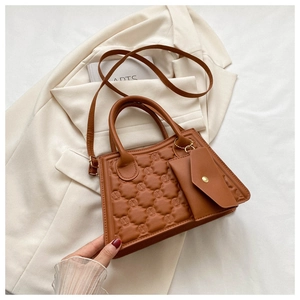 Detail of caramel crossbody bag with quilted texture and small coin pouch on white blazer