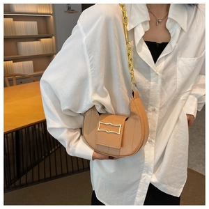 Détail du sac demi-lune marron clair avec chaîne dorée et boucle métallique moderne