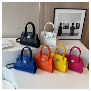 Detail view of colorful leather handbags featuring silver turn-lock hardware and top handles