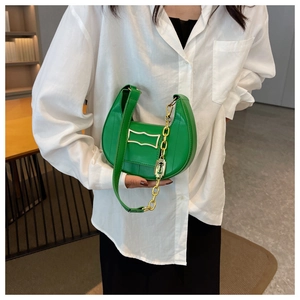 Detailed view of a green crescent moon bag featuring a gold chain and leather strap accents