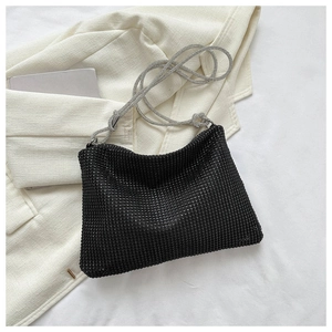 Detail of black rhinestone shoulder bag with silver beaded chain strap on white blazer