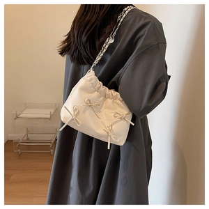 Detail of cream leather pleated bucket bag with bow accents and silver chain strap
