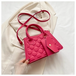 Detail of rose red quilted square bag with gold hardware and small envelope pouch