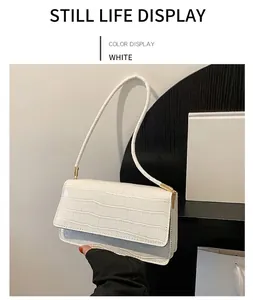 Détail de la texture motif crocodile blanc sur le petit sac à main avec attaches métalliques