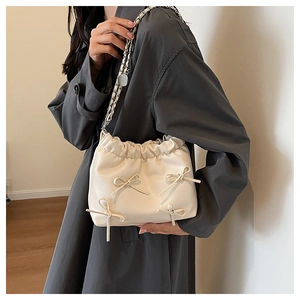 Close-up of cream pleated bucket bag with bow details and silver chain strap