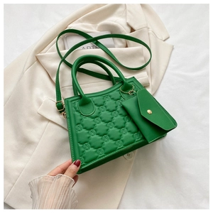 Detail of green quilted leather crossbody bag with embossed logo and mini coin purse charm