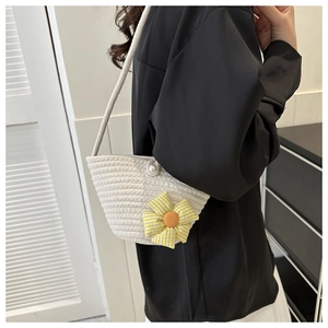 Dettaglio borsa a secchiello intrecciata crema con grande fiore e chiusura di perla