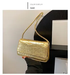 Détail d'un sac à main doré en similicuir crocodile avec texture brillante et moderne