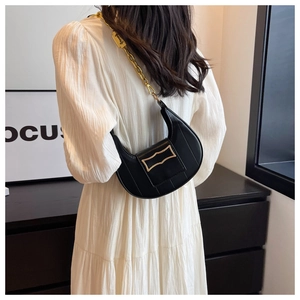 Détail du sac croissant en cuir noir avec coutures verticales et chaîne dorée épaisse