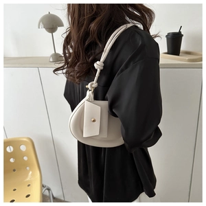 Minimalist white crescent shoulder bag with knot strap detail shown in lifestyle setting