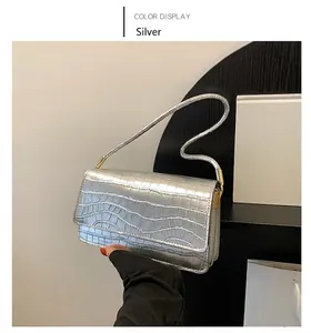 Détail d'un sac à bandoulière argenté avec motif crocodile et rabat rectangulaire chic