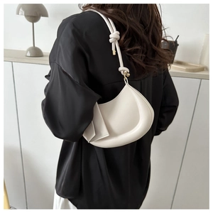 Detail of a white crescent shoulder bag with unique knotted strap and gold hardware