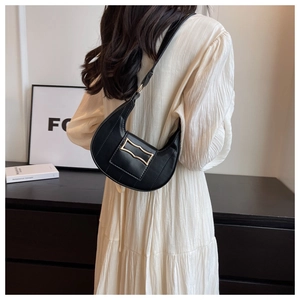 Détail du sac à bandoulière noir en forme de croissant avec boucle dorée sur modèle