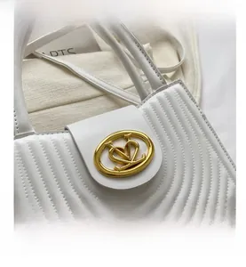 Detail van witte gewatteerde imitatielederen handtas met gouden hartvormige metalen gesp