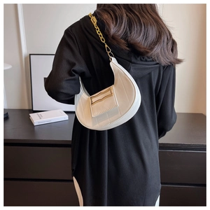 Détail du sac demi-lune crème avec bandoulière en chaîne dorée et boucle métallique