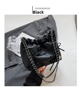 Detail view of black pleated PU leather tote bag with bow accent and silver chain strap