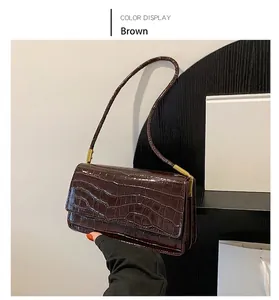 Détail de l'imprimé crocodile café sur un sac sous le bras en cuir brillant