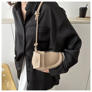 Close-up of minimalist crescent bag with knotted strap and small side pouch detail
