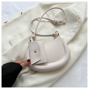 Detail of beige half-moon shoulder bag with minimalist knotted strap and small pouch
